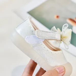 Détail de chaussure princesse pour fille avec un grand nœud pailleté et tissu nacré