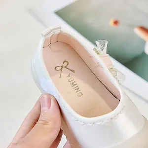 Vue détaillée de chaussures de princesse en satin blanc avec logo doré et doublure rose