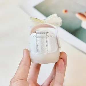 Détail de chaussures bébé argent perlé avec nœud en maille et semelle en caoutchouc