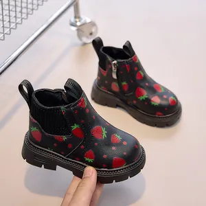 Detail of kids black combat boots featuring red strawberry prints and side zipper