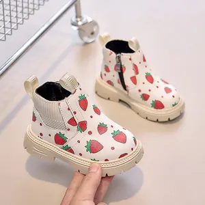 Detail of kids' white boots with red strawberry print and side zipper closure