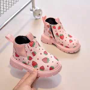 Detail of pink toddler boots with strawberry print and side zipper on a rubber sole