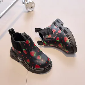 Close-up of strawberry print patterns on black kids boots with non-slip thick rubber soles