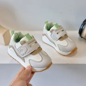 Detail of toddler sneakers featuring a cute cartoon pig emblem and velcro strap closure
