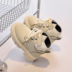 Detail view of cream suede kids boots with ribbed collar and velcro strap on textured sole