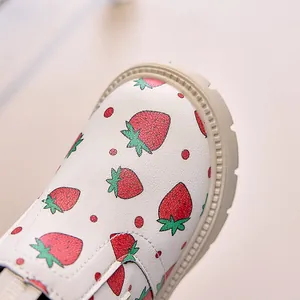 Detailed macro view of the cream children's boot with red strawberry pattern and thick sole