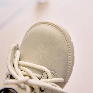 Detailed macro view of children's beige suede boots showing fine stitching and rubber sole