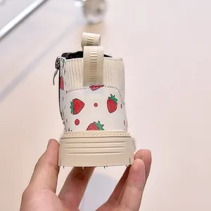 Detail of children's white leather boots featuring strawberry prints and side zipper