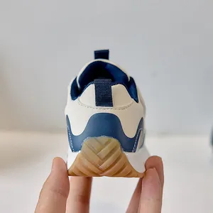 Detail of baby sneakers showing non-slip rubber soles and navy heel pull tabs