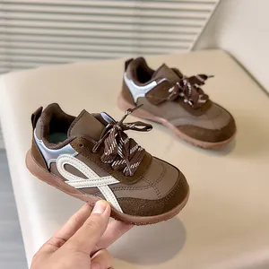 Detailopname van bruine kinder-retrosneakers met suèdetextuur en witte strepen