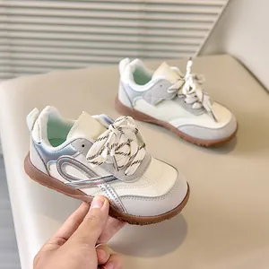 Detail van retro kindersneakers van beige leer, grijs suède en bruine rubberen zool