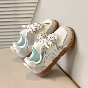 Detail van retro kindersneakers met beige leren panelen en bruine rubberen zool