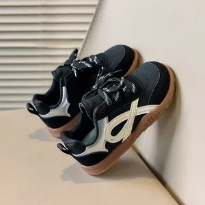 Detail van zwarte suède kindersneakers met zilveren strepen en een bruine rubberen zool