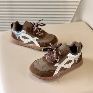 Detail van retro kindersneakers van donkerbruin suède met zilveren metalen accenten