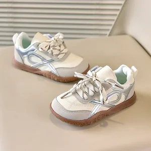 Detail van retro kindersneakers in crème leer met zilveren details en een rubberen zool