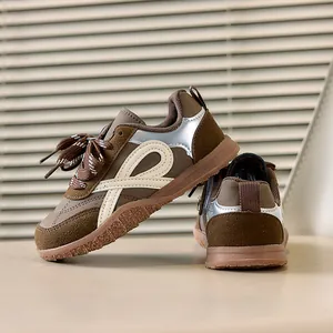 Detail van retro kindersneakers met bruin suède en zilveren lederen accenten