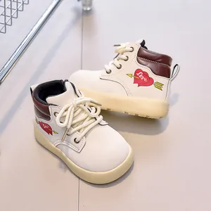 Detail view of children's cream leather boots with brown trim and heart embroidery