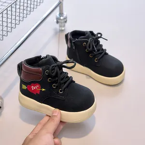Close-up of kids' black boots featuring a love heart print and chunky cream soles