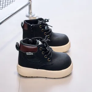 Detail of kids black leather boots with side zipper and smile logo on cream sole