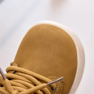 Close-up of yellow nubuck leather toe and woven laces on children's casual boots