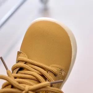 Macro detail of mustard yellow kid's ankle boot with textured leather and round toe cap