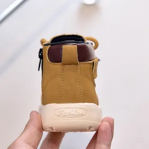 Close-up of kids yellow leather boots showing side zipper, velcro strap and thick sole