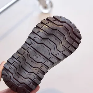 Close-up of children's brown boots featuring non-slip rubber soles with deep wave patterns