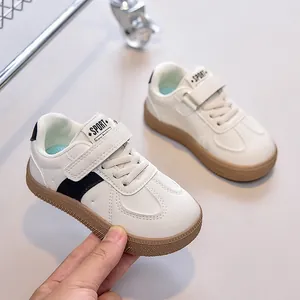 Détail de baskets pour enfants en similicuir blanc et semelle en caoutchouc brun