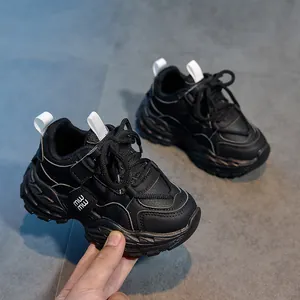 Détail d'une basket noire pour enfant avec semelle épaisse et étiquette MW sur carrelage