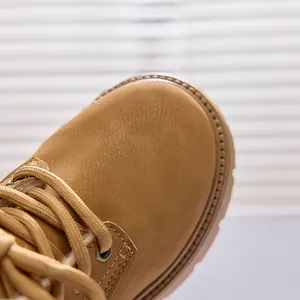Close-up of matte yellow leather boots with round laces and silver metal eyelets