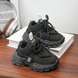 Close-up of black kids chunky sneakers with hook-and-loop straps on a wooden table