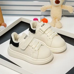 Détail de baskets blanches pour enfants avec double velcro et accents noirs au talon
