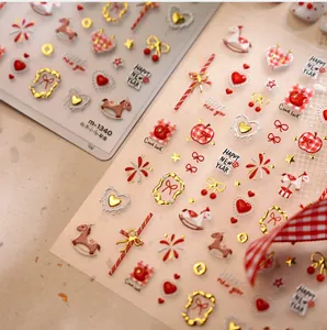 Macro detail of 3D gold embossed New Year nail stickers with red hearts and rocking horse