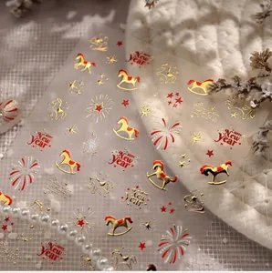 Close-up of New Year nail stickers featuring red horses and golden festive patterns