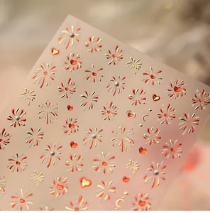 Macro detail of festive nail art stickers featuring gold fireworks and red heart designs