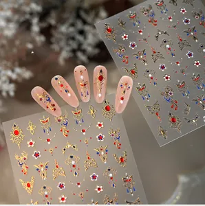 Macro shot of M1324 nail decals with golden embroidery, red gems, and floral patterns