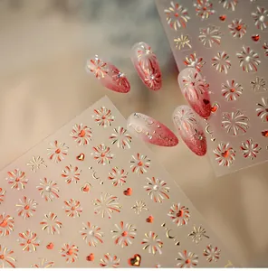Macro shot of festive nail stickers with red and gold fireworks, stars and hearts
