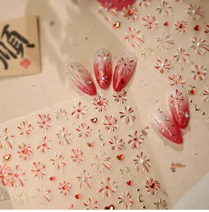 Detailed view of red and gold firework nail stickers with 3D pearls and hearts