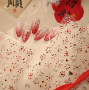 Macro detail of red and gold firework nail stickers with elegant pearl accents