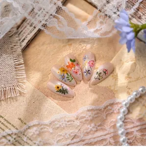 Macro view of almond shaped nail art with floral patterns and delicate rhinestones