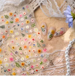 Close-up of floral nail stickers with gold outlines on natural nails and lace background
