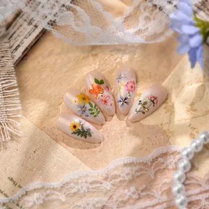 Floral almond press-on nails with dried flowers and rhinestones on soft pink base