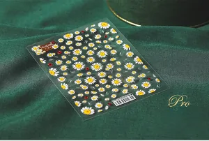 Vue détaillée de stickers ongles 5D marguerites et coccinelles sur fond velours vert