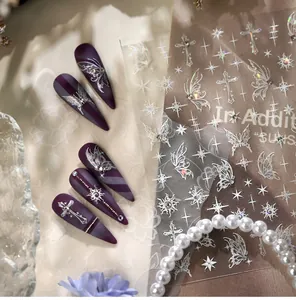 Macro detail of dark purple matte stiletto nails with holographic butterfly and cross decals