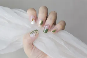 Close-up of 5D embossed nail stickers with dark green art, gold foil, and pearls