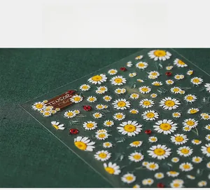 Stickers 5D pour ongles avec marguerites blanches et coccinelles sur un support dépoli