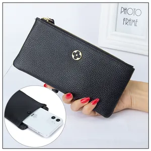 Close-up of black pebble leather clutch featuring a gold clover logo and phone compartment