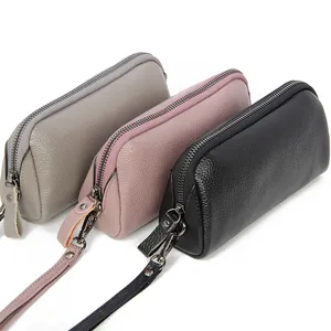 Three long leather clutches in grey, pink, and black with pebble grain texture and wristlets