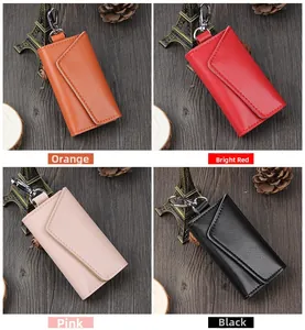 Litchi pattern leather key pouches in orange, red, pink, and black colors on wooden background