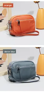 Detailed view of leather coin purses in orange and denim blue with triple zippers